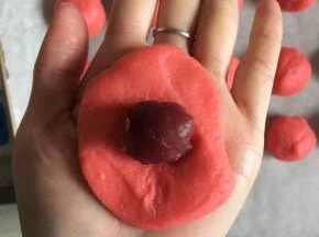 取一个面团压扁包入一点树莓麻薯