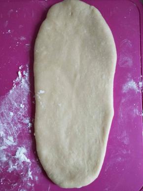 案板、擀面杖上撒少许面粉，取一个面团从中间开始，分别往上下两个方向擀，擀成长舌状。