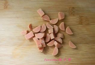 将火腿肠剥去外皮，对半切开，再切小丁；