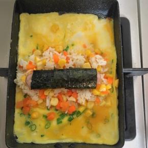 玉子烧里放少许植物油，倒入蛋液，等蛋液7、8分熟放入米饭，香肠裹上海苔放到米饭上，然后把一端的蛋饼翻过来盖住米饭，成为蛋包饭