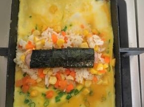 玉子烧里放少许植物油，倒入蛋液，等蛋液7、8分熟放入米饭，香肠裹上海苔放到米饭上，然后把一端的蛋饼翻过来盖住米饭，成为蛋包饭