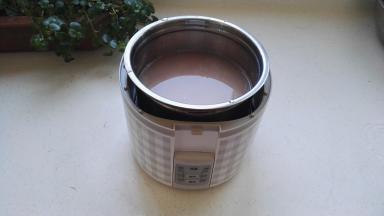 把米全部放进最大的不锈钢容器中，加入适量的清水，把不锈钢容器放入机体内。