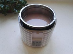 把米全部放进最大的不锈钢容器中，加入适量的清水，把不锈钢容器放入机体内。