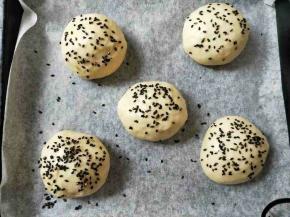 面团分十份，揉圆，表面刷蛋液，沾上黑芝麻。送入烤箱发酵，边上放盆热水，大约半小时左右，2倍大即可。