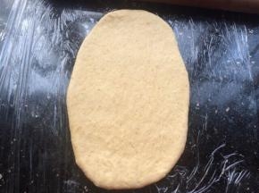 把松弛好的面团，用擀面杖擀成牛舌状。