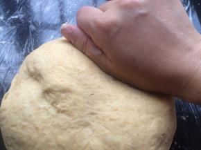 把面团拿出操作台上用手轻轻按压排气。