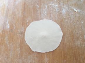 取一个剂子，用擀面杖擀成中间略厚，四周薄的饺子皮