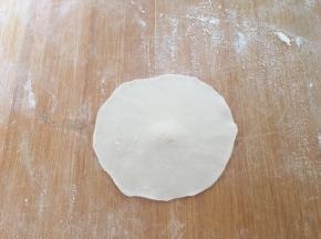 取一个剂子，用擀面杖擀成中间略厚，四周薄的饺子皮