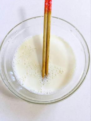 找一个大一点儿的碗，倒入白糖和牛奶，用筷子搅拌均匀至白糖融化！
