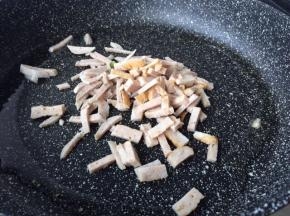 然后不粘锅用中火烧热倒入适量的花生油烧热，再放入猪肉丸跟肉卷炒1-2分钟左右。