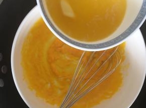 搅拌到蛋黄浓稠时分次倒入融化的黄油，继续不停搅拌，注意这个时候大锅内的水还是微微沸腾的
