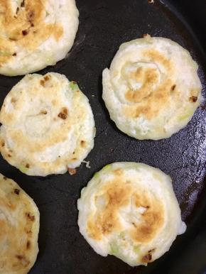 不沾锅内倒入适量的植物油，将葱油饼放在上面小火煎至变色再翻面煎至金黄色即可出锅