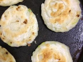 不沾锅内倒入适量的植物油，将葱油饼放在上面小火煎至变色再翻面煎至金黄色即可出锅