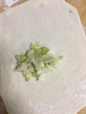 舀适量的葱陷放在擀好的面饼上