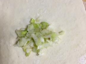 舀适量的葱陷放在擀好的面饼上