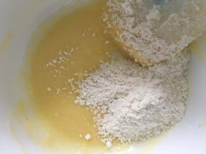 把之前混合好的椰蓉粉倒入蛋白黄油中，翻拌均匀