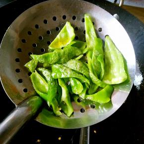 青椒块不用放在油里炸，只要放在漏勺里，另一只手拿勺子舀油浇至表面起泡即可。