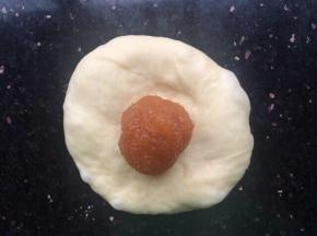 拿一份小面包用手掌按压一下，放入菠萝馅收口。