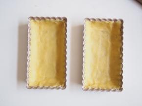 派盘抹上一层黄油，撒上薄薄一层低筋面粉，将多余面粉抖出。冷藏好的面团分成两份，轻轻将面团压至充满整个派盘