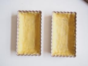 派盘抹上一层黄油，撒上薄薄一层低筋面粉，将多余面粉抖出。冷藏好的面团分成两份，轻轻将面团压至充满整个派盘