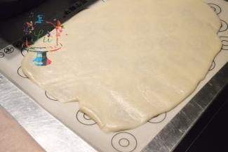 擀面杖抹一些手粉，均匀推开糯米皮。宽度一定要够。可以用自己切好的戚风条的宽度比对一下。4个面一共大概需要多宽。四边切整齐