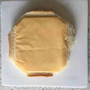 另一片吐司片上先铺一片百吉福芝士片，多余的芝士片稍微修剪一下