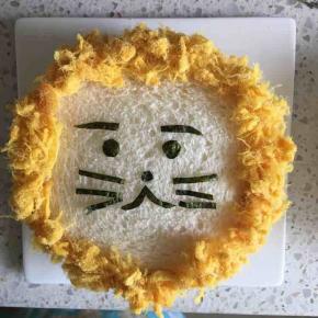 然后粘上肉松，盖在铺了芝士片、火腿片和瓜果的吐司片上，小狮子三明治就做好了