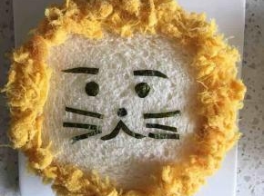然后粘上肉松，盖在铺了芝士片、火腿片和瓜果的吐司片上，小狮子三明治就做好了