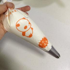 在裱花袋中装入一个裱花嘴，再把打发好的奶油继续装入裱花袋。