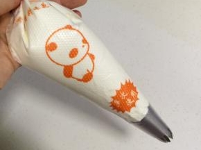 在裱花袋中装入一个裱花嘴，再把打发好的奶油继续装入裱花袋。