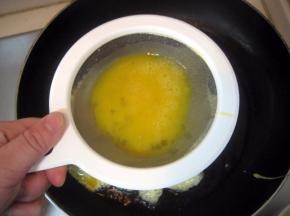 烧至八成热时，将蛋液由漏勺淋到油中； 快速用筷子在将蛋液划散，不要让蛋液结块；