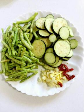 茄子去蒂清洗干净后切成片，豆角抽掉筋，掐成小段儿洗净，沥干水份，蒜瓣剥皮剁碎，生姜切成丝，干辣椒切成段儿备用！
