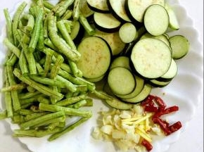 茄子去蒂清洗干净后切成片，豆角抽掉筋，掐成小段儿洗净，沥干水份，蒜瓣剥皮剁碎，生姜切成丝，干辣椒切成段儿备用！
