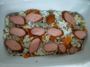 烤碗里放入米饭，脆皮肠切片放在米饭上。