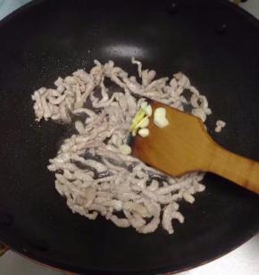 炒至肉丝变色后放入姜丝与蒜，翻炒几下。