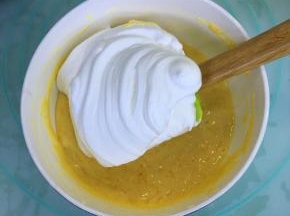 取三分之一的蛋白霜到蛋黄糊里，用刮刀翻拌均匀。