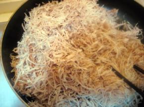 将撕好的猪肉丝均匀撒入锅内，将火力转至最小；