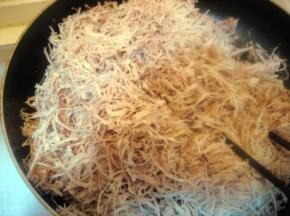 将撕好的猪肉丝均匀撒入锅内，将火力转至最小；