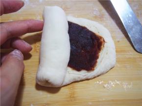 放入豆沙馅，从一端卷起，捏紧收口。