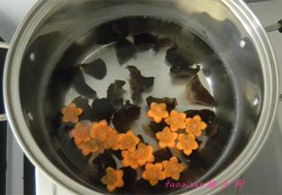 煮锅里水热后，倒入水发的木耳和切好的胡萝卜花片，焯烫一下捞出来，过凉水；