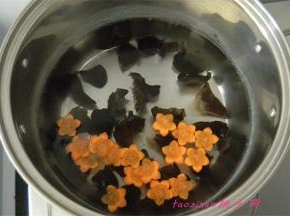 煮锅里水热后，倒入水发的木耳和切好的胡萝卜花片，焯烫一下捞出来，过凉水；