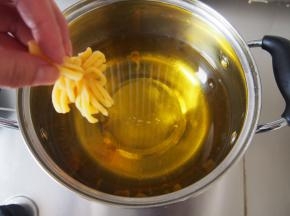 油锅烧至6成热，倒提着菊花坯子放入油锅中炸制