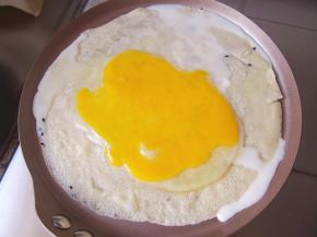 一面煎熟后翻面，磕上一个鸡蛋，摊开