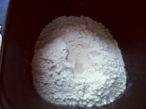 最后放入高筋面粉，再面粉顶部挖个小洞，注意不要挖到液体，把酵母粉放入洞里，再用周边的面粉把酵母粉盖起来。