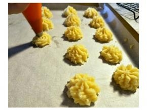 预热烤箱180上下火。用8齿中号花嘴。裱花袋放置到高的杯子，中间刮入面糊。裱花袋排出空气。高1cm的地方挤出曲奇花。