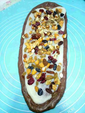 将发酵好的面团评论分成3.4份静置一个，麻薯面团也是一样的数量，然后用把麻薯上面放一层保鲜膜，把麻薯擀成牛舌状后把面包面团放在麻薯上面继续擀，使面包面团盖过麻薯面团就可以翻过来包馅料了