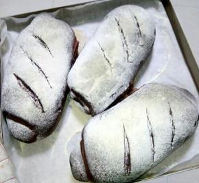 把做成型的面包放入烤盘里面用刀片割几道口，撒一些面粉放入烤箱进行第二次发酵