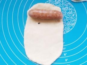 取一份面团，擀薄，卷入香肠。