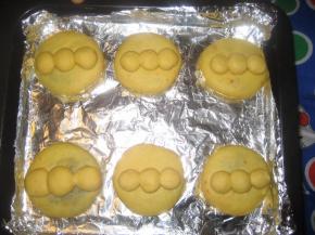 然后烤盘中的每个面团上放三个小圆形面片，并用手压紧；