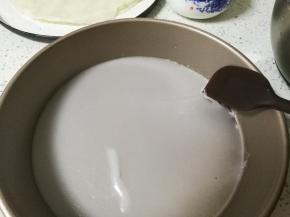 用小号硅胶刮刀沿着披萨盘边缘慢慢的挑起凉皮，拿出来，小心烫手